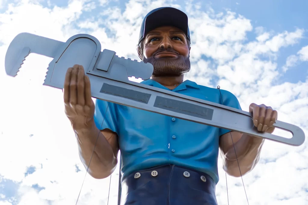 Muffler Man in Dallas, Georgia Roadside Attractions. He is holding a big wrench against a blue sky with clouds.